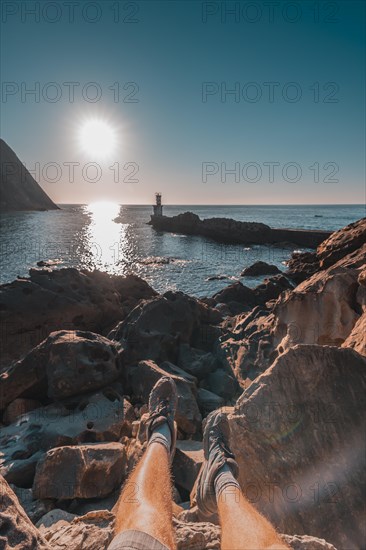 Feet of a young man sitting at the Lighthouse in Pasajes San Juan near San Sebastian