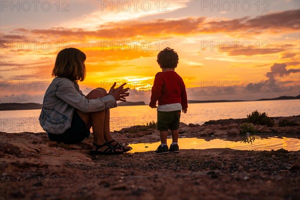 Mother with her son on the promenade at sunset in San Antonio Abad