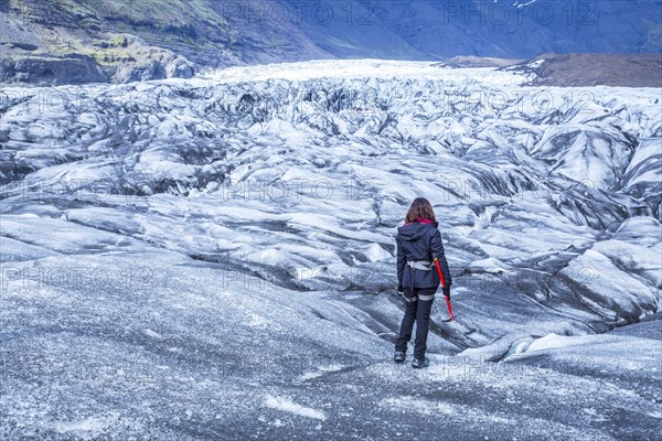 A young woman on her back with booties and hammer on the trekking of the Svinafellsjokull glacier. Iceland