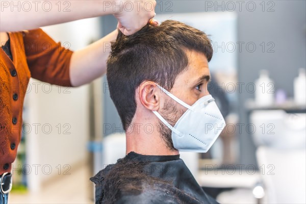 Hairdressers after the Coronavirus pandemic. Hairdresser with face mask and protective screen