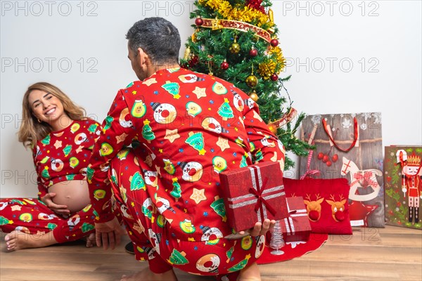 Young couple sitting by Christmas tree