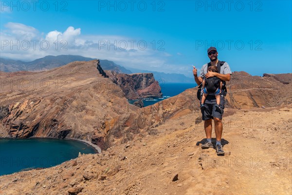 A father with his baby in summer in Ponta de Sao Lourenco looking at the landscape and the sea