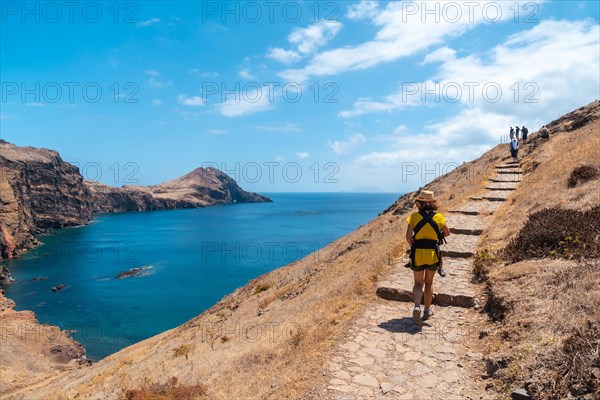 A young mother with her baby in her backpack in Ponta de Sao Lourenco on the parking path