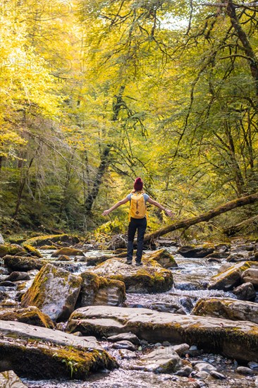 A young hiker at sunset on the river on the trail to the Holtzarte suspension bridge