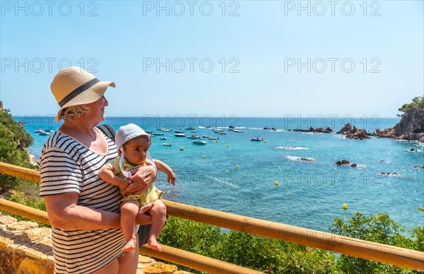 A grandmother and grandson having fun in the summer in Cala Canyet next to the town of Tossa de Mar. Girona