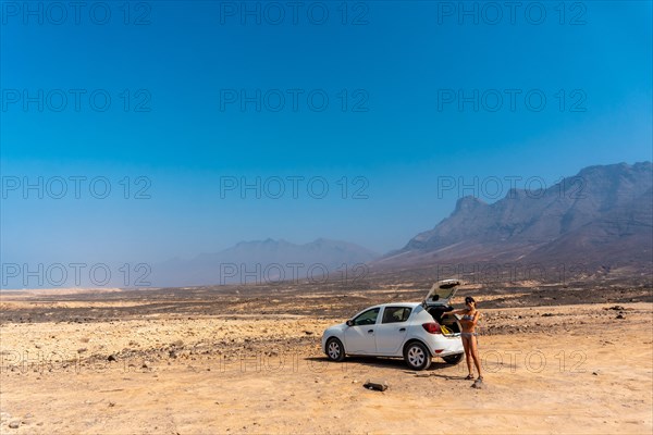 A young girl with the rental car on the Cofete beach of the Jandia natural park