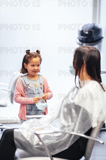 Client sitting waiting for the dye to dry and meanwhile talking to her daughter. Reopening with security measures for hairdressers in the Covid-19 pandemic