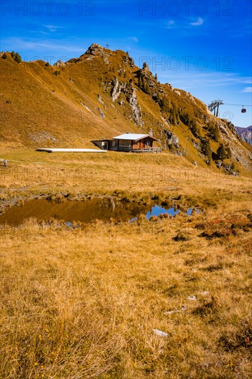 Mountain lake in rocky mountain landscape in autumn with cable car and hut