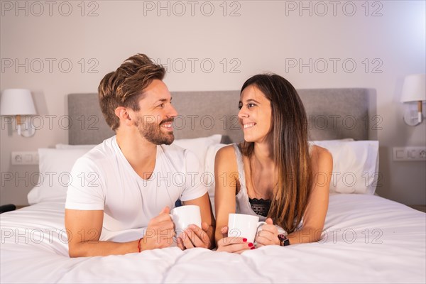 Looks of a couple in love in pajamas having breakfast in the hotel bed