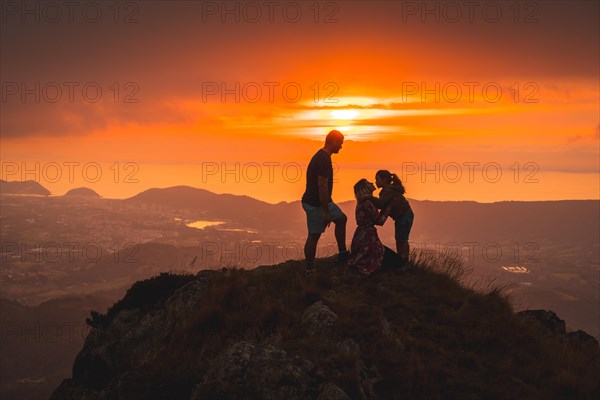 Parents with their son on top of a mountain at sunset