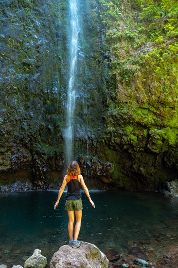 A young woman looking at the impressive waterfall at the Levada do Caldeirao Verde