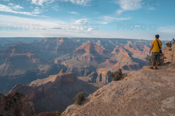 A man in a yellow shirt enjoying the sunset views at Mojave Point in Grand Canyon. Arizona