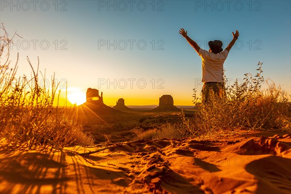 A lifestyle guy with a hat and open arms at dawn in Monument Valley
