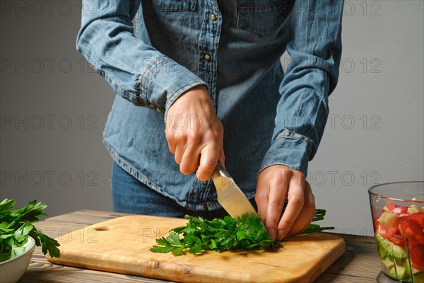 An unrecognizable woman cuts cilantro into large pieces