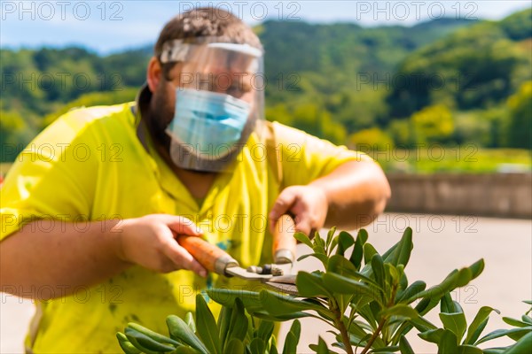 Worker in a recycling factory or clean point and garbage with a face mask and plastic protective screen