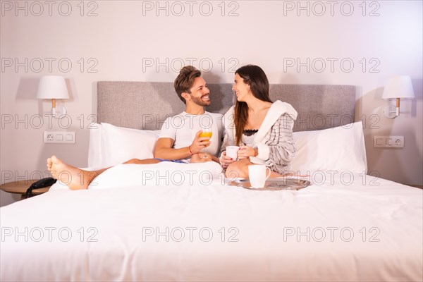 A couple in love in pajamas having breakfast in the hotel bed in the morning