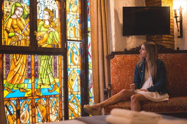 Young blonde caucasian woman in a white dress and denim jacket enjoying a beautiful medieval hotel in the town of Olite in Navarra. Spain