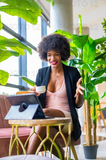 Black skinned girl with afro hair wearing a pink dress and black jacket