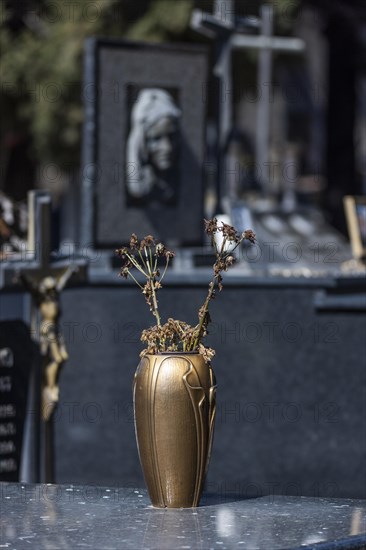 Vase with withered flowers on a grave in a cemetery