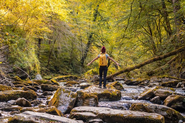 A young hiker at sunset on the river on the trail to the Holtzarte suspension bridge