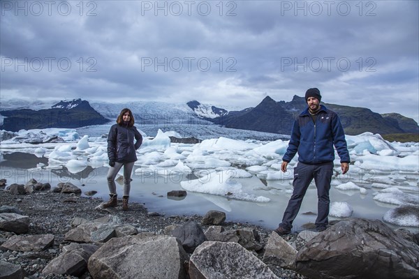 A couple with a backpack looking at the Jokulsarlon Ice Lake in the golden circle of southern Iceland