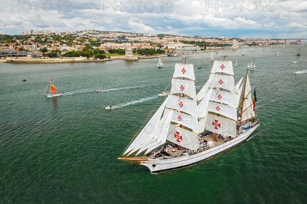 Aerial drone view of tall ships with sails sailing in Tagus river towards the Atlantic ocean in Lisbon