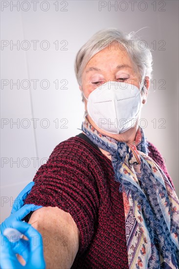 Female doctor injecting the coronavirus vaccine to an elderly lady. Antibodies