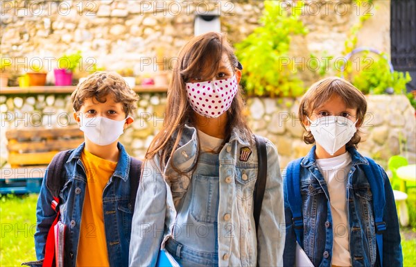 Three brother children with face masks ready for going back to school. New normality