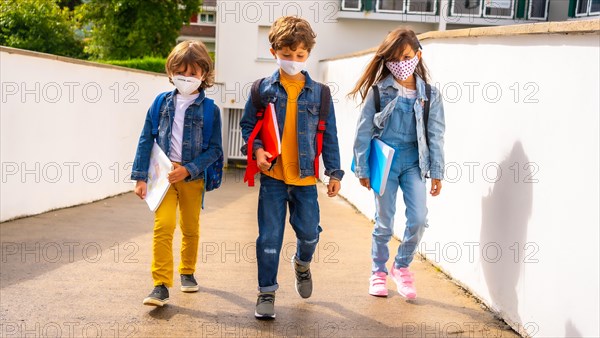 Three brothers with face masks ready to go back to school. New normality