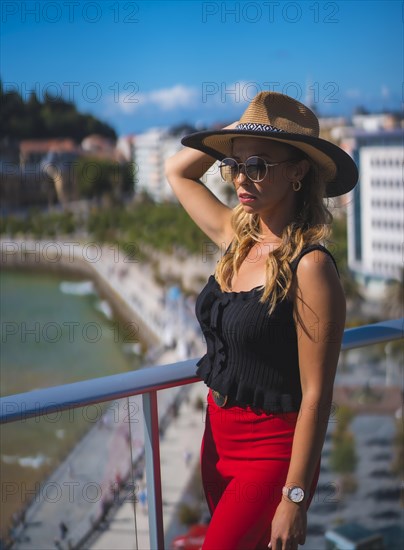 Portrait of a blonde woman spending her holidays in a luxury hotel on a terrace wearing a hat