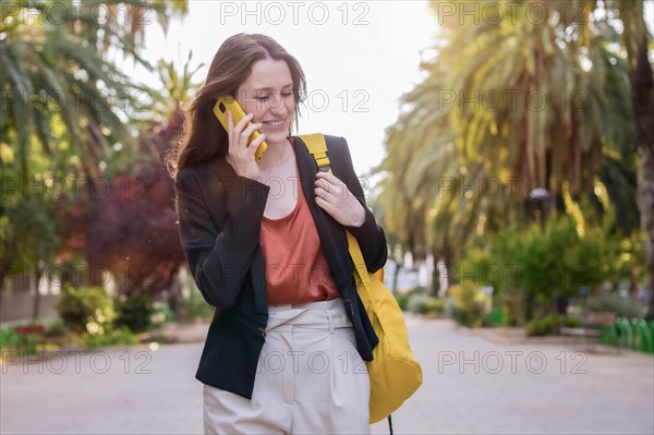 Casual woman with a yellow bag talking to the mobile phone outdoors