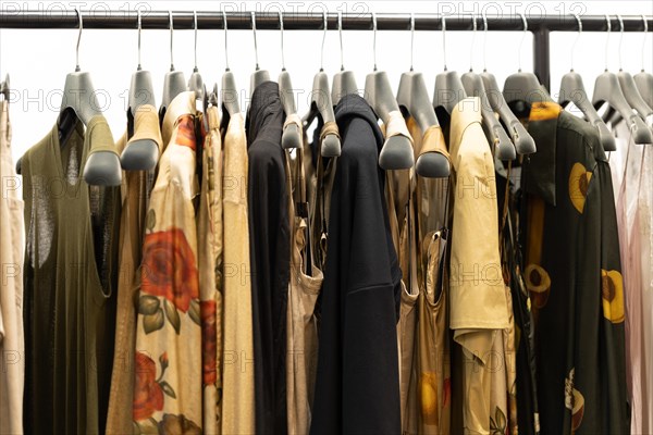 Clothes and dresses in neutral shades on a hanger in the shop. Mid shot