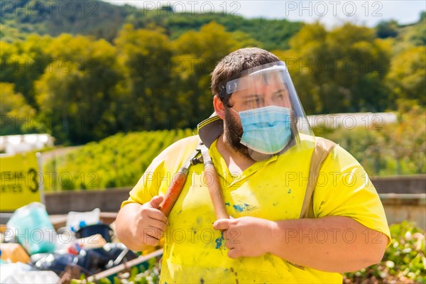 Worker in a recycling factory or clean point and garbage with a face mask and plastic protective screen