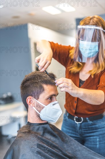 Hairdressers after the Coronavirus pandemic. Caucasian hairdresser with face mask and protective screen