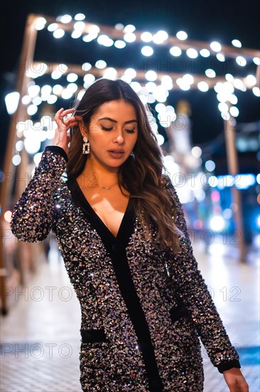 Christmas lifestyle. Portrait a young brunette Caucasian woman in a fashionable dress with sequins