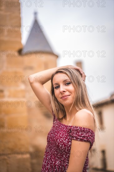 Portrait of a blonde woman smiling next to a medieval castle in summer