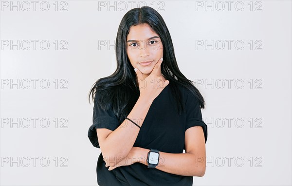 Portrait of young woman with hand on chin looking at camera. Smiling latin girl with hand on chin looking at camera