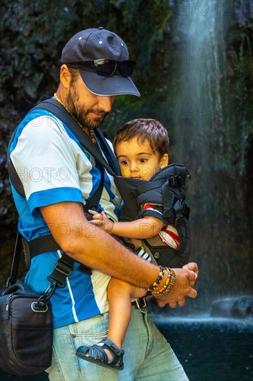A father with his son in summer at the waterfall at Levada do Caldeirao Verde