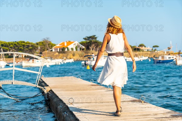 A young woman in a dress in Cadaques walking along the sea