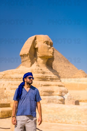 A young tourist near the Great Sphinx of Giza dressed in blue and a blue turban