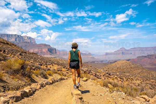 A young woman with green shirt resting on the South Kaibab Trailhead trekking. Grand Canyon
