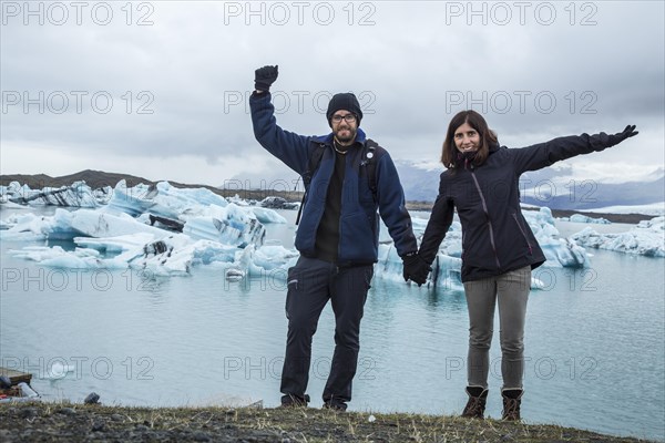 A couple with a backpack looking at the Jokulsarlon Ice Lake in the golden circle of southern Iceland