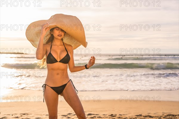 Summer portrait with a beautiful young woman wearing an oversized straw hat