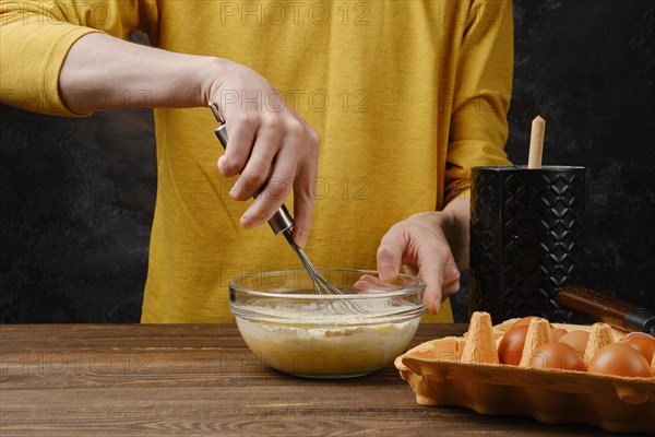 Close up of male hand whisking egg and flour in a glass bowl