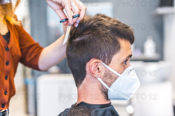 Hairdressers after the Coronavirus pandemic. Hairdresser with face mask and protective screen