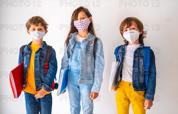 Three children with face masks ready to go back to school. New normality