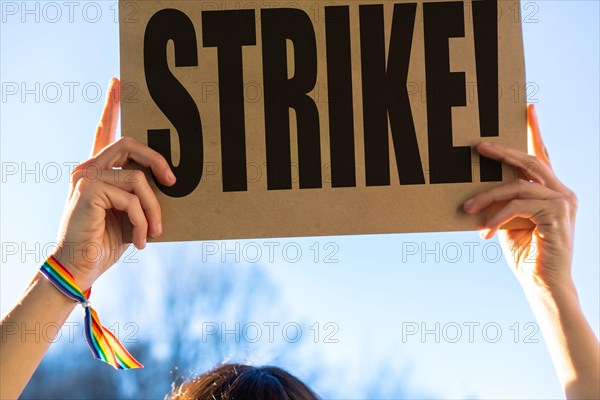 A female activist holding a sign with the slogan of the hollywood actors and writers strike with the blue sky in the background