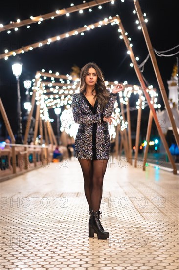 Winter lifestyle at Christmas. Brunette Caucasian girl in a fashionable dress with sequins and black high heels