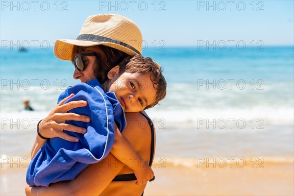 Mother hugging her son by the sea on vacation