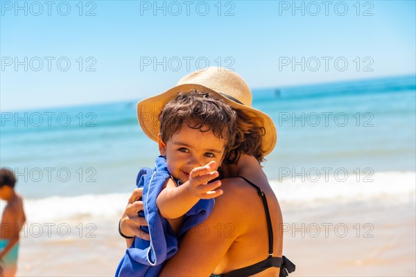 Mother hugging and having fun with her son by the sea